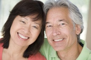 Couple with Dental Implants Smiling With Heads Touching