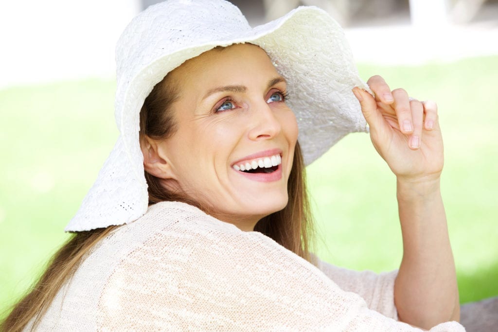 Woman With White Hat Smiling Outdoors Woman With White Hat Smiling Outdoors
